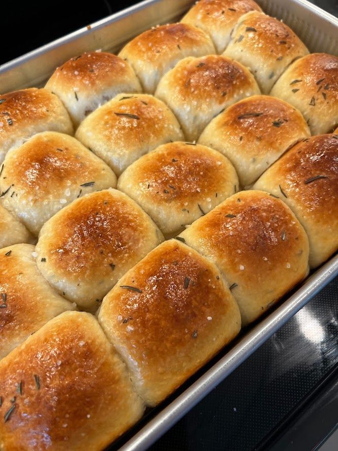 A pan filled with rolls is sitting on a stove.