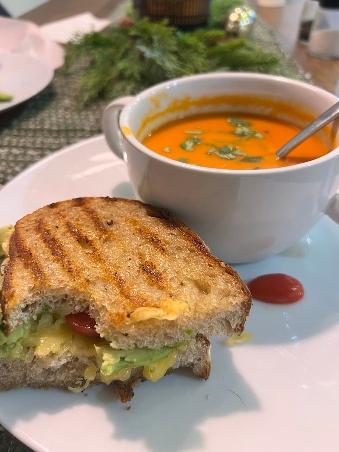 A grilled cheese sandwich and a cup of soup on a plate.