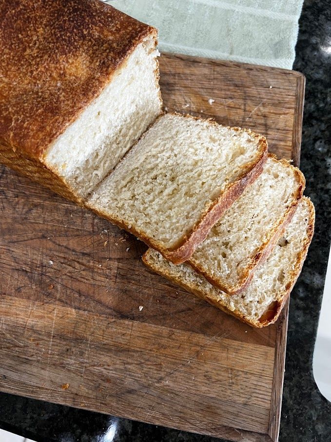 A loaf of bread is sitting on a wooden cutting board.