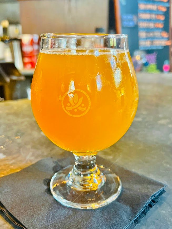A glass of beer is sitting on a napkin on a table.