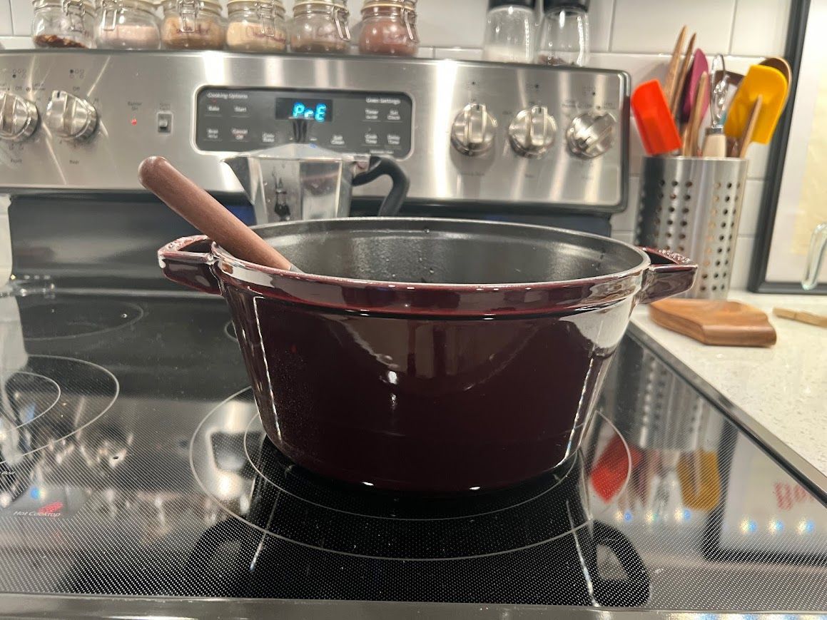 A pot is sitting on top of a stove with a wooden spoon in it.
