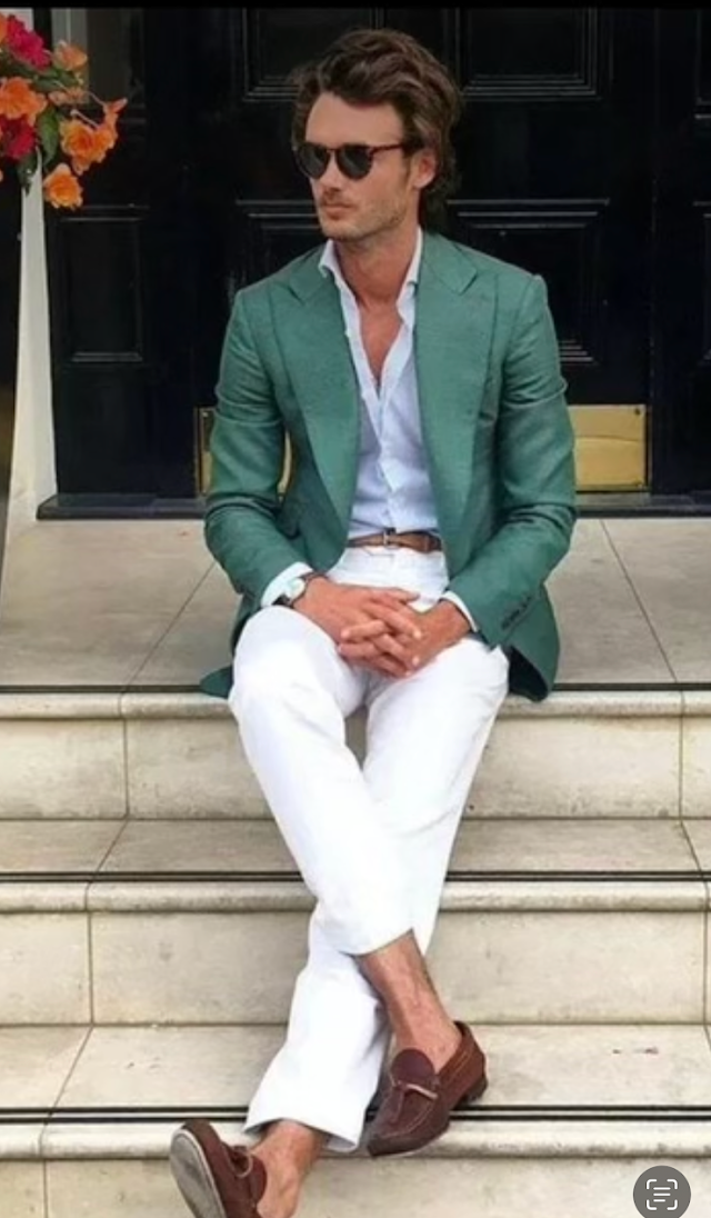 A man in a green jacket and white pants is sitting on a set of stairs.