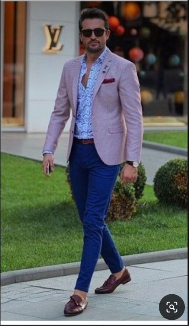 A man wearing a pink jacket and blue pants is walking down the street.