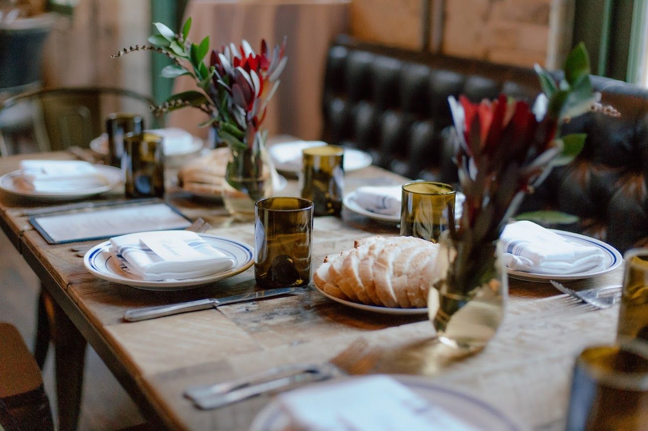 A table with plates , glasses , and vases of flowers on it.