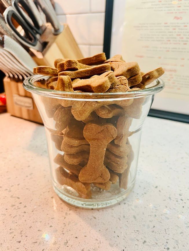 A glass jar filled with dog treats on a counter.