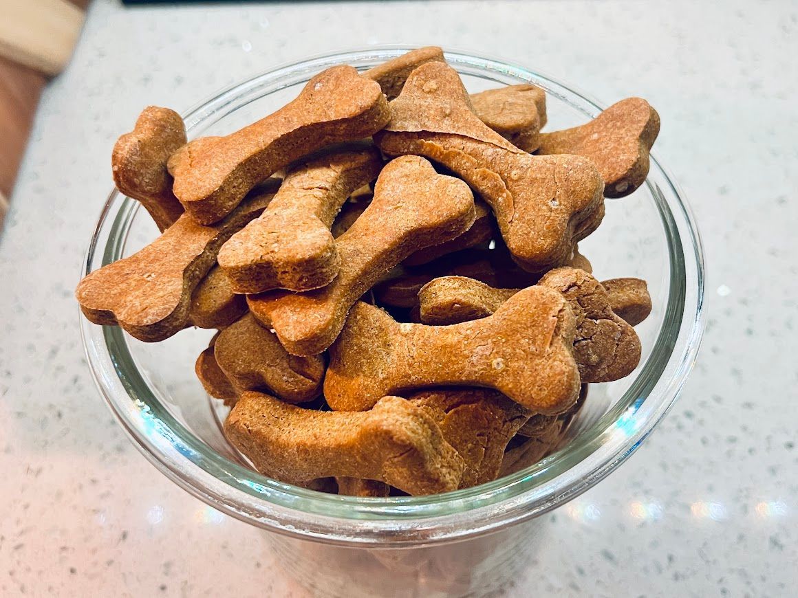 A glass bowl filled with dog treats in the shape of bones.