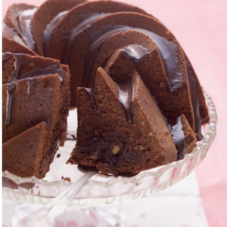 A bundt cake with chocolate icing on a glass plate