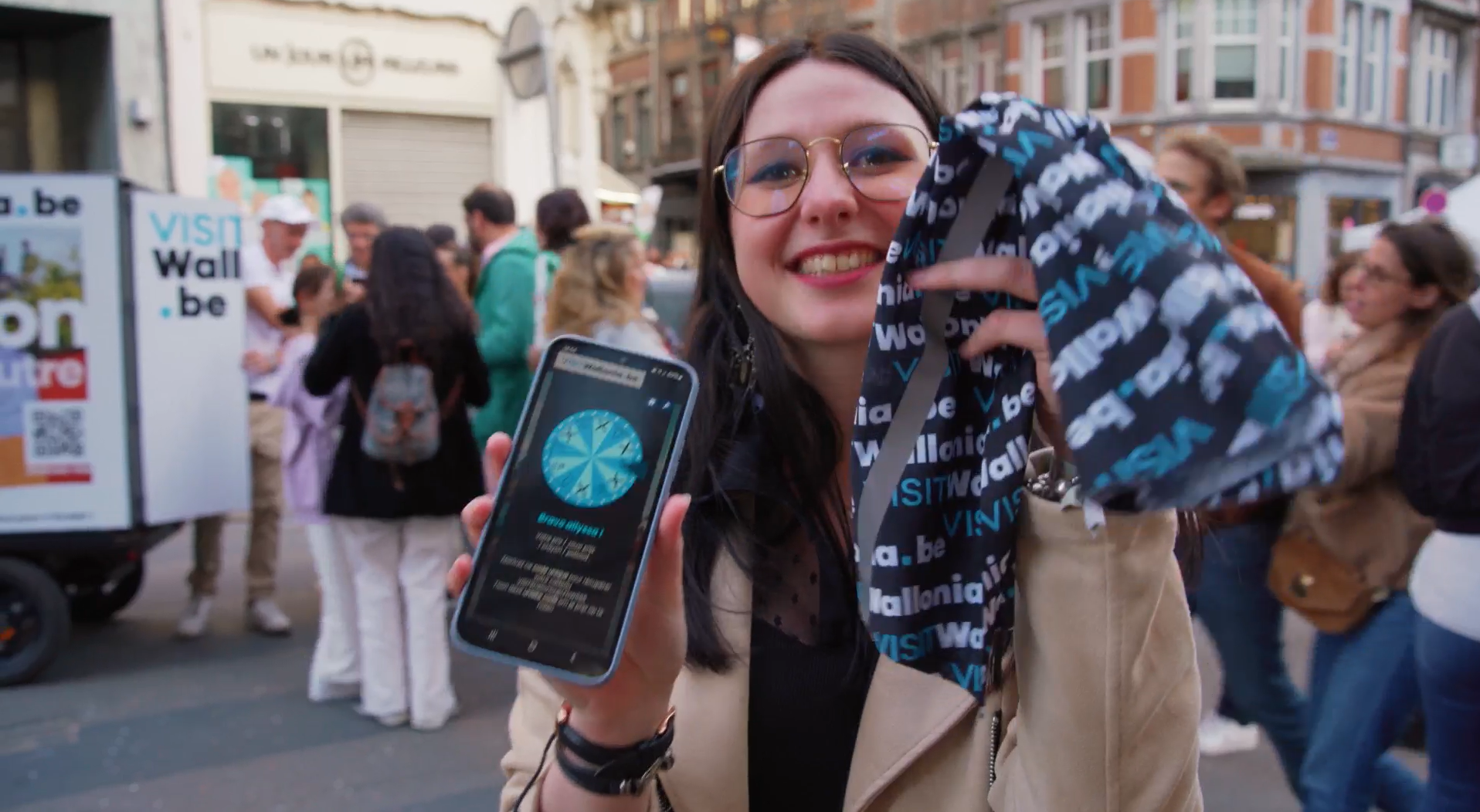 Jeune fille aux Wallos de Namur devant les vélos EYE SCREEN montrant le jeux concours et les goodies VISIT Wallonia