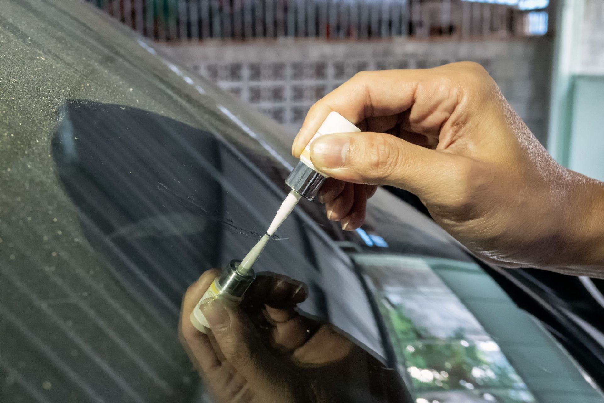 A person is applying a brush to a car windshield.