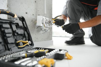 Open furnace closet with exposed wiring and tools on the floor in a hallway