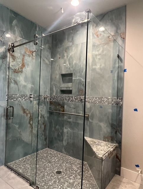 A bathroom with a walk in shower with a glass door.