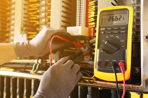 An electrician is using a multimeter to test a circuit board.