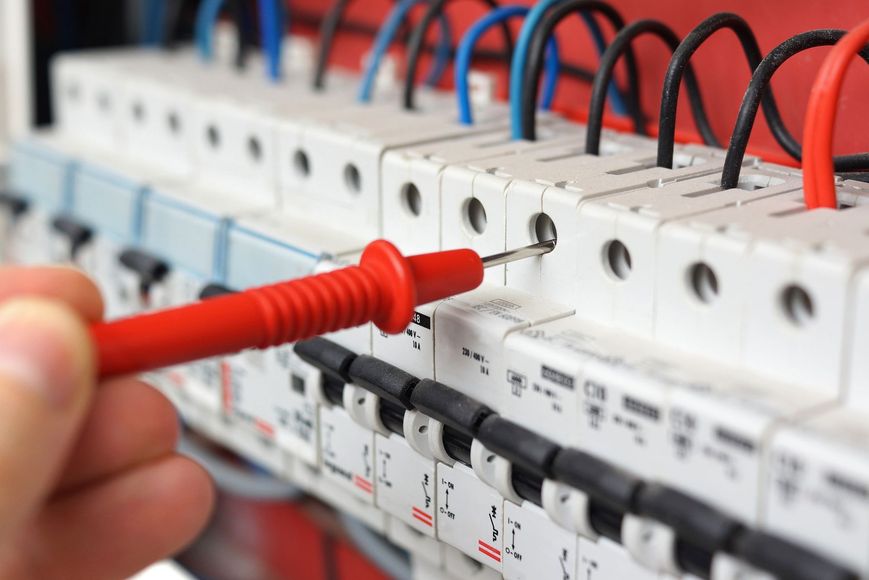 A person is using a multimeter to test a circuit breaker.