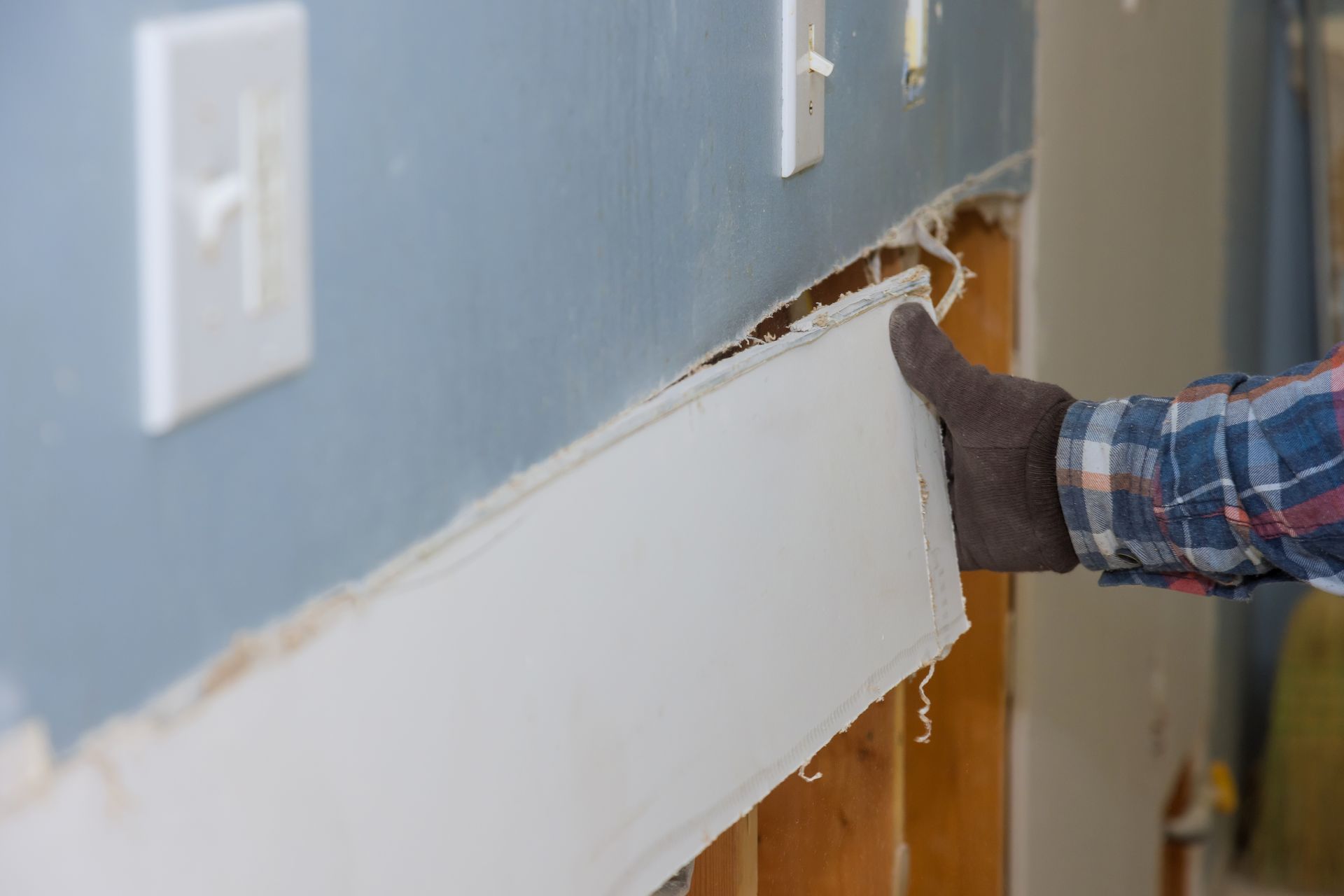 A person is holding a piece of trim on a wall.