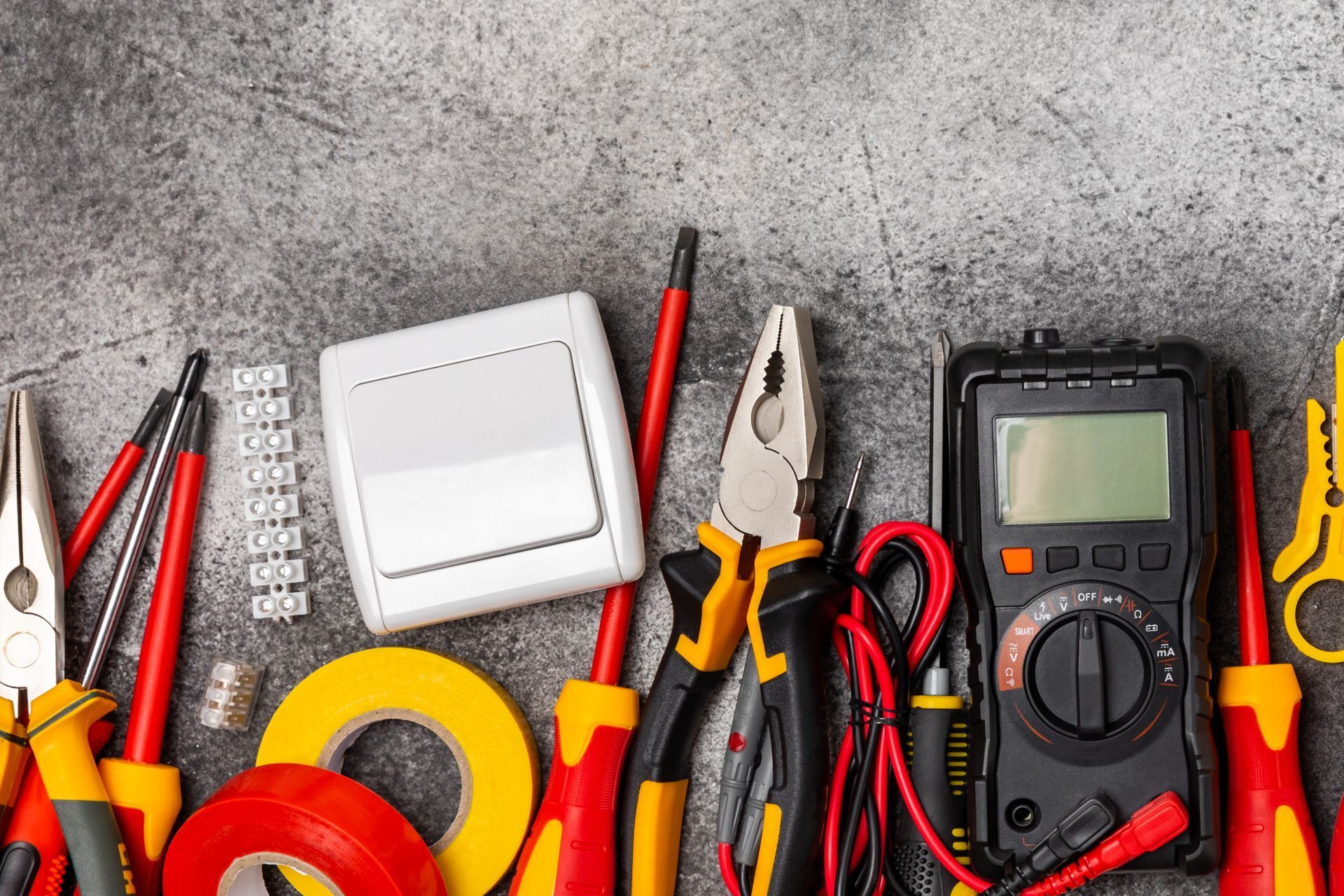 A bunch of electrician 's tools are sitting on a table.