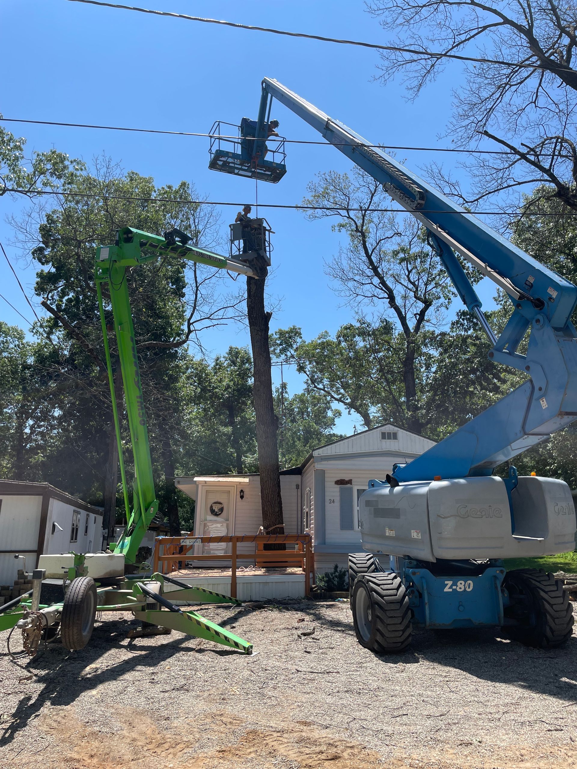 A crane is cutting a tree in front of a house.