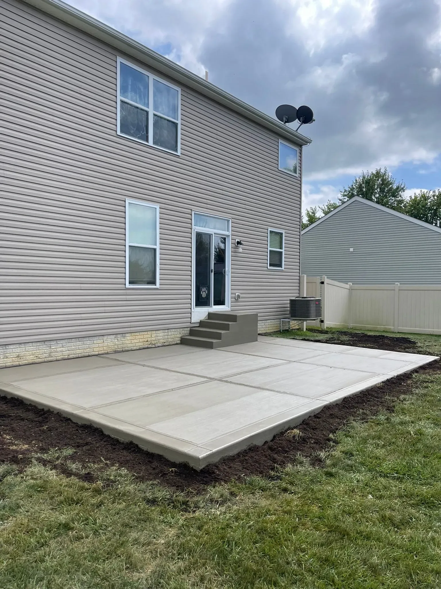 A large house with a concrete patio in front of it.