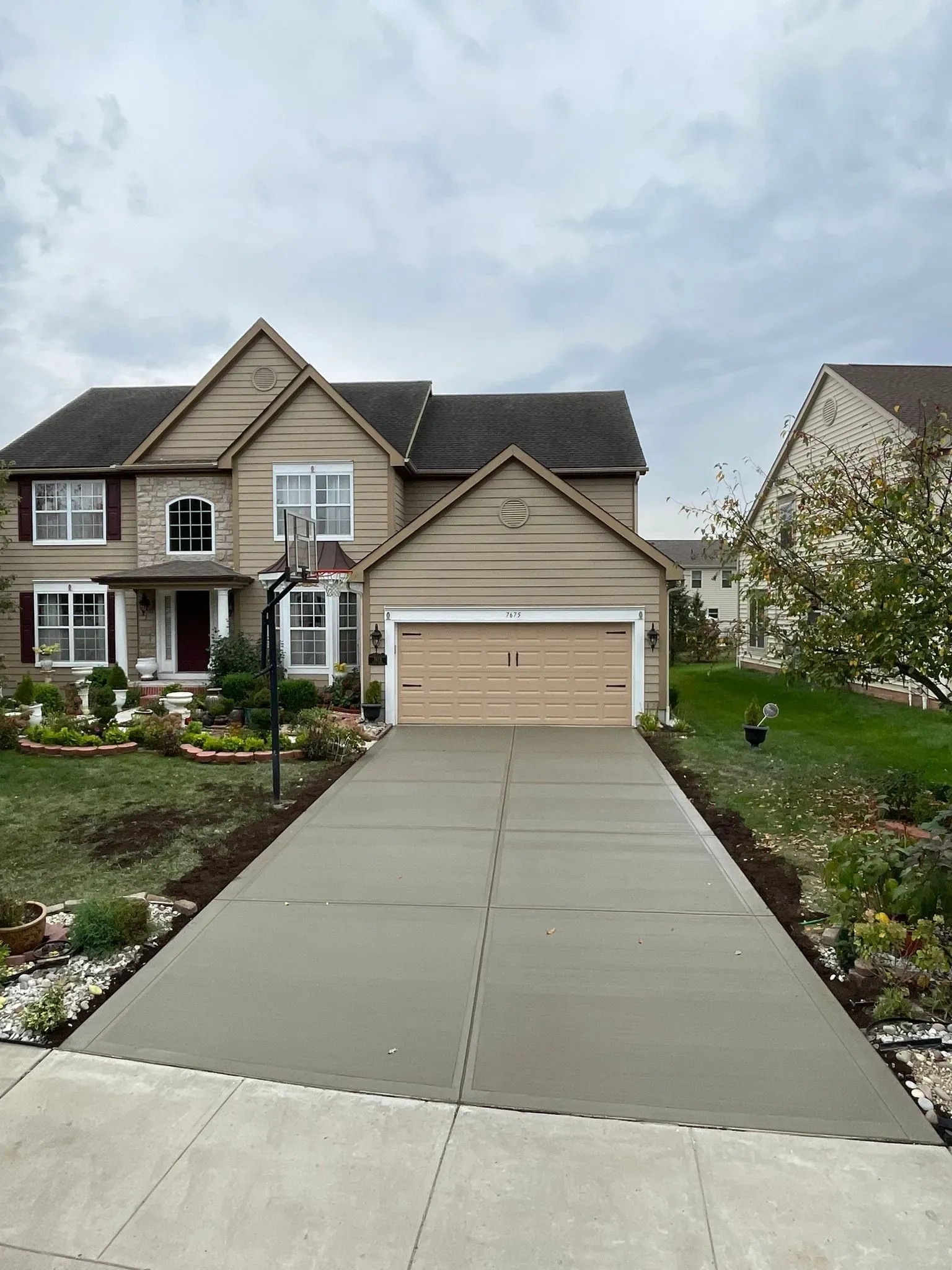 A large house with a basketball hoop in front of it and a driveway leading to it.