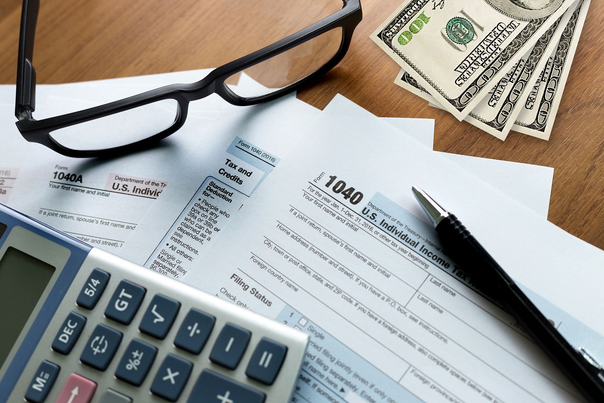 A pen calculator and glasses are on top of a 1040 tax form