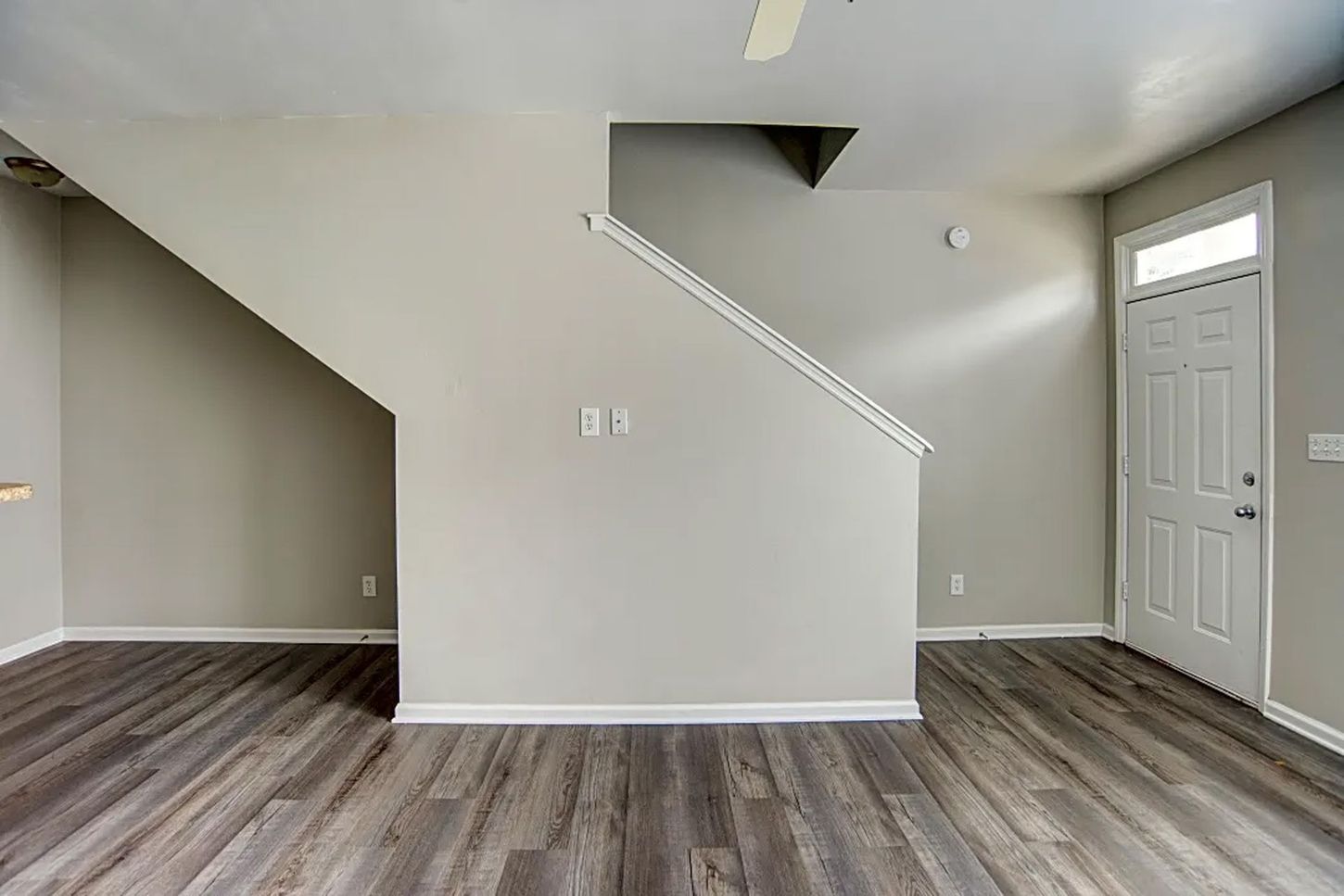 An empty living room with hardwood floors and stairs in a house.