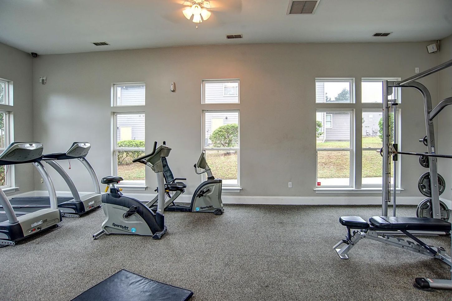 A gym with treadmills , exercise bikes , and a bench.