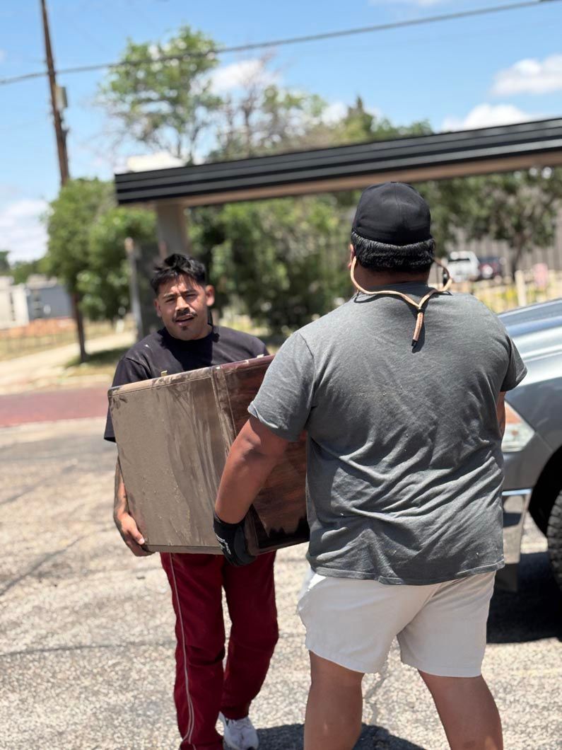 Two men are standing next to each other carrying boxes.