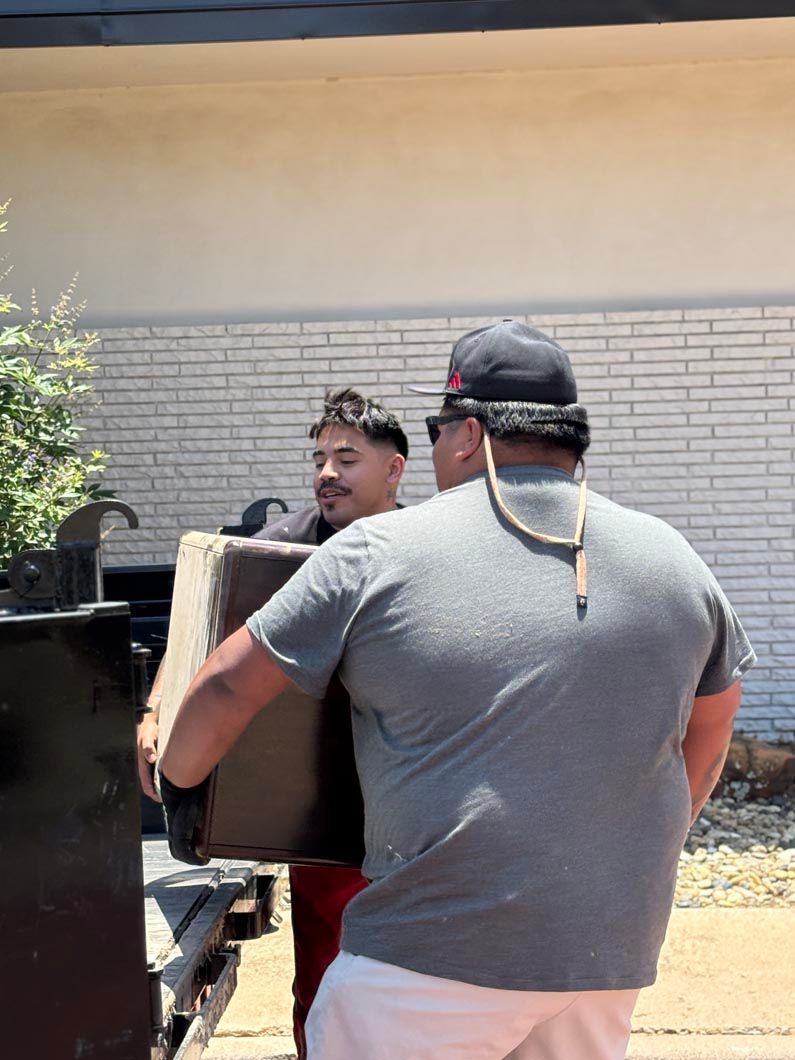 A man is carrying a box in front of a brick building.