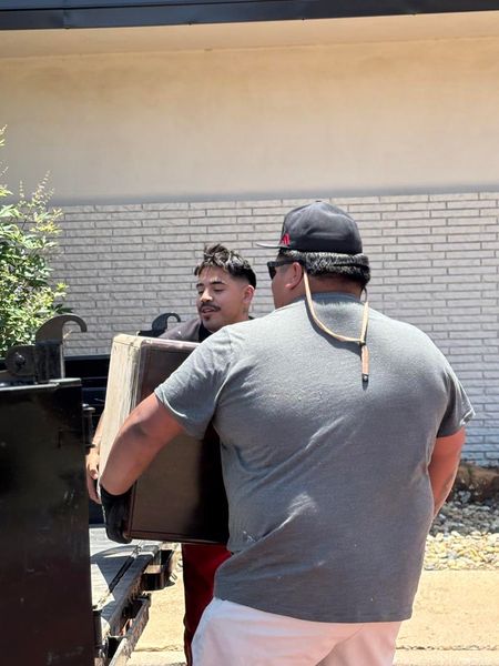 A man is carrying a box in front of a brick building.