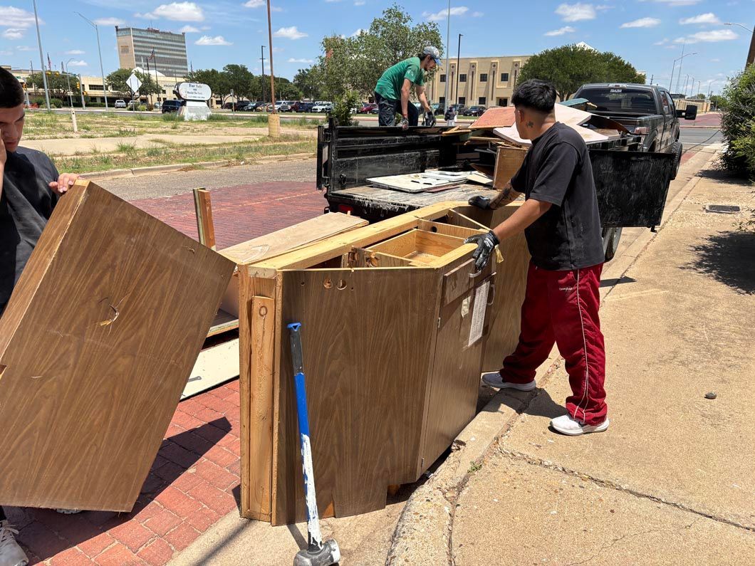 Two men are carrying wooden boxes on a sidewalk next to a truck.
