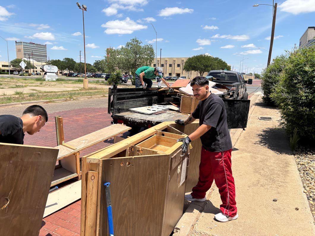 Two men are loading a truck with wooden boxes on a sidewalk.