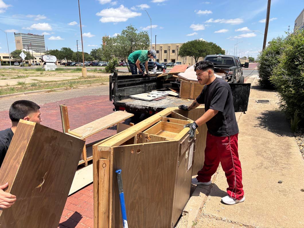 A man in red pants is carrying a piece of wood.