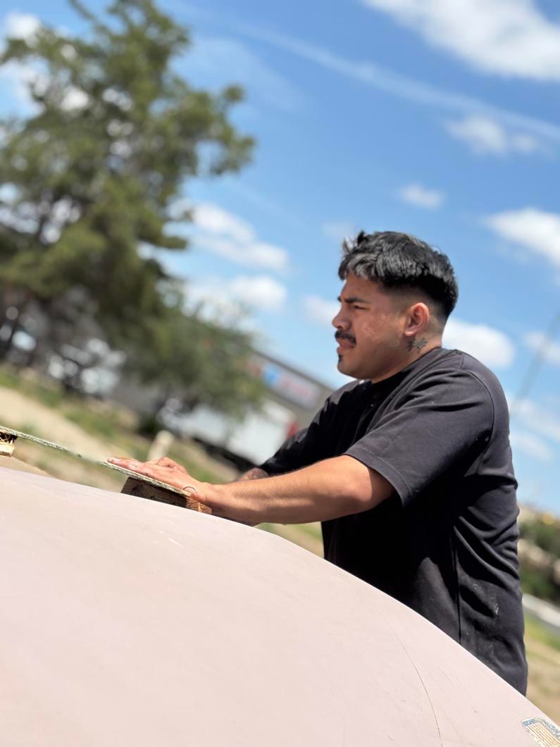 A man in a black shirt is sitting on the hood of a car.
