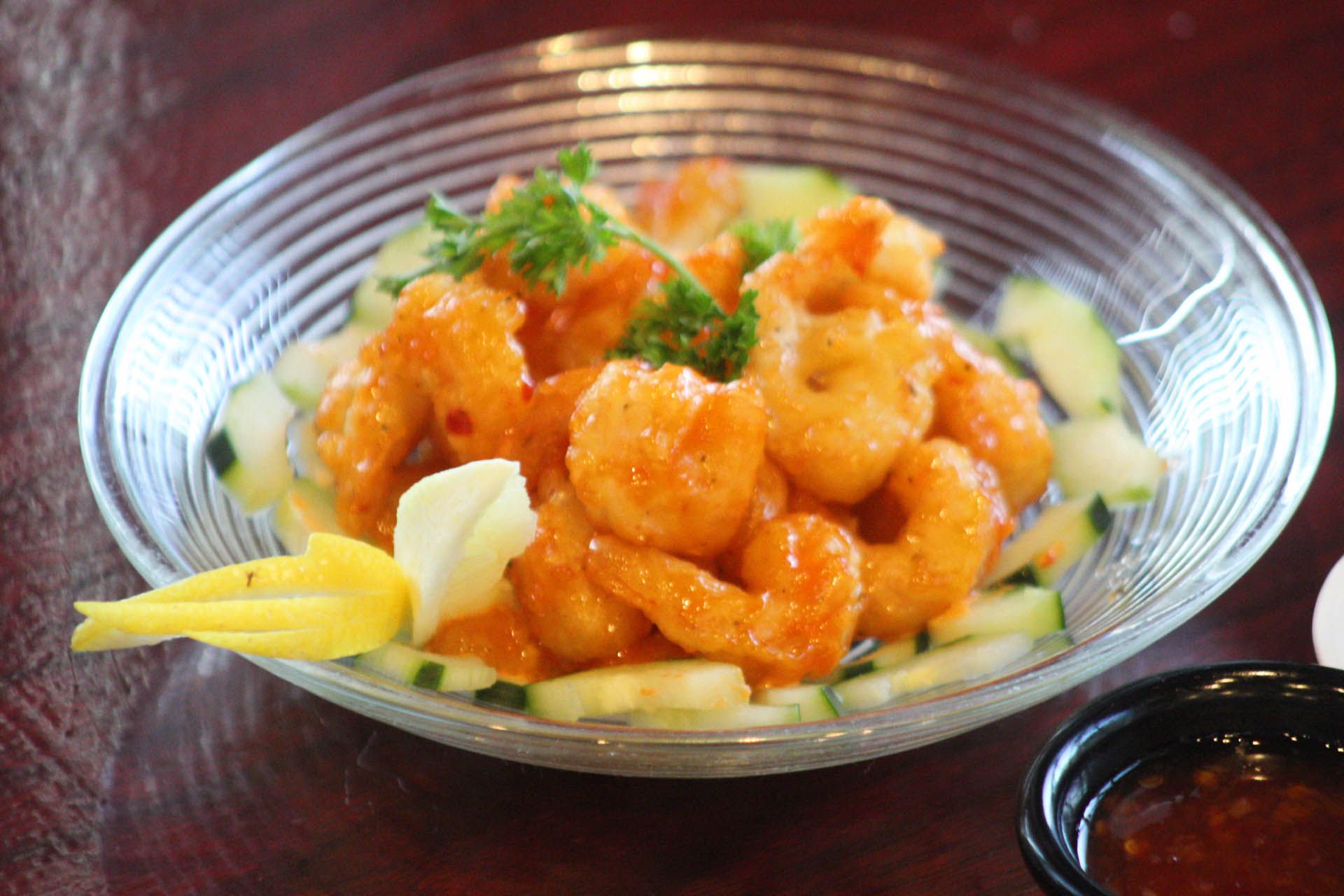 A close up of a plate of shrimp and cucumbers on a table.