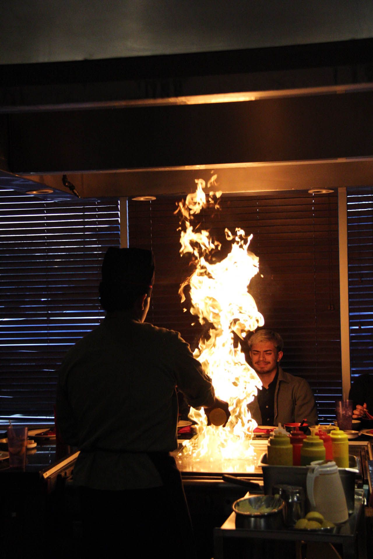 A man is standing in front of a stove with flames coming out of it