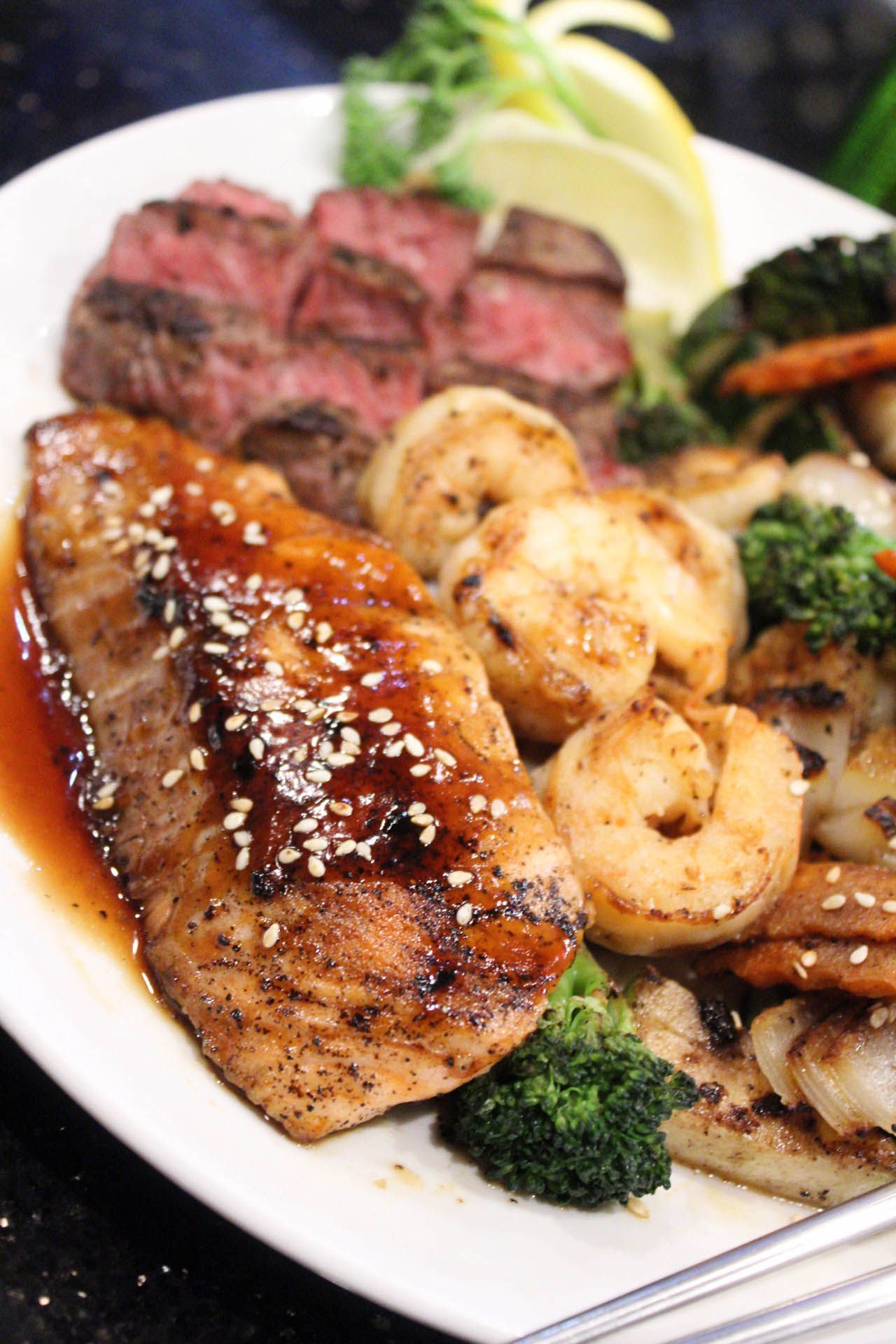 A white plate topped with steak , shrimp , broccoli and vegetables.