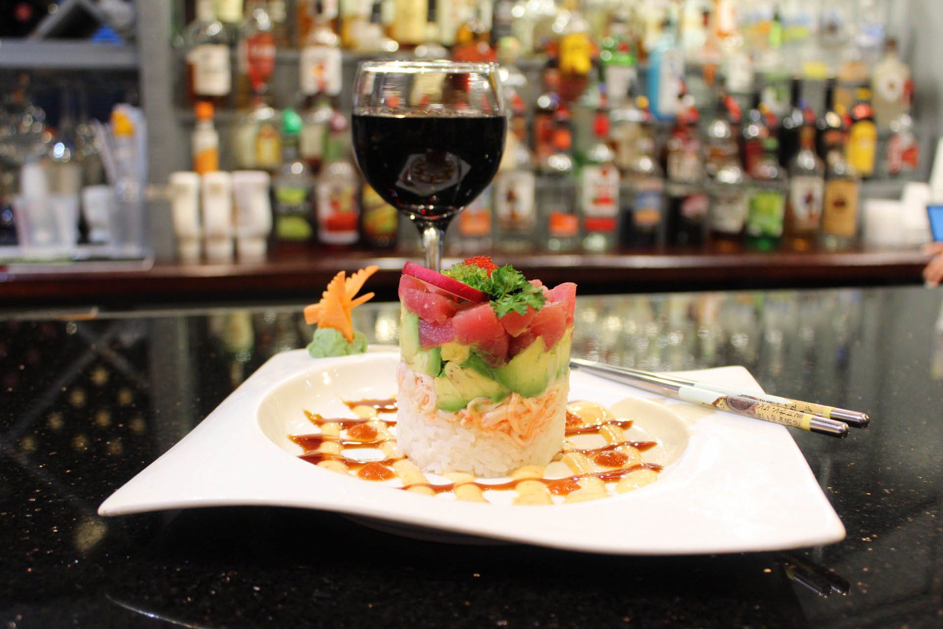 A plate of food with a glass of wine on a bar.