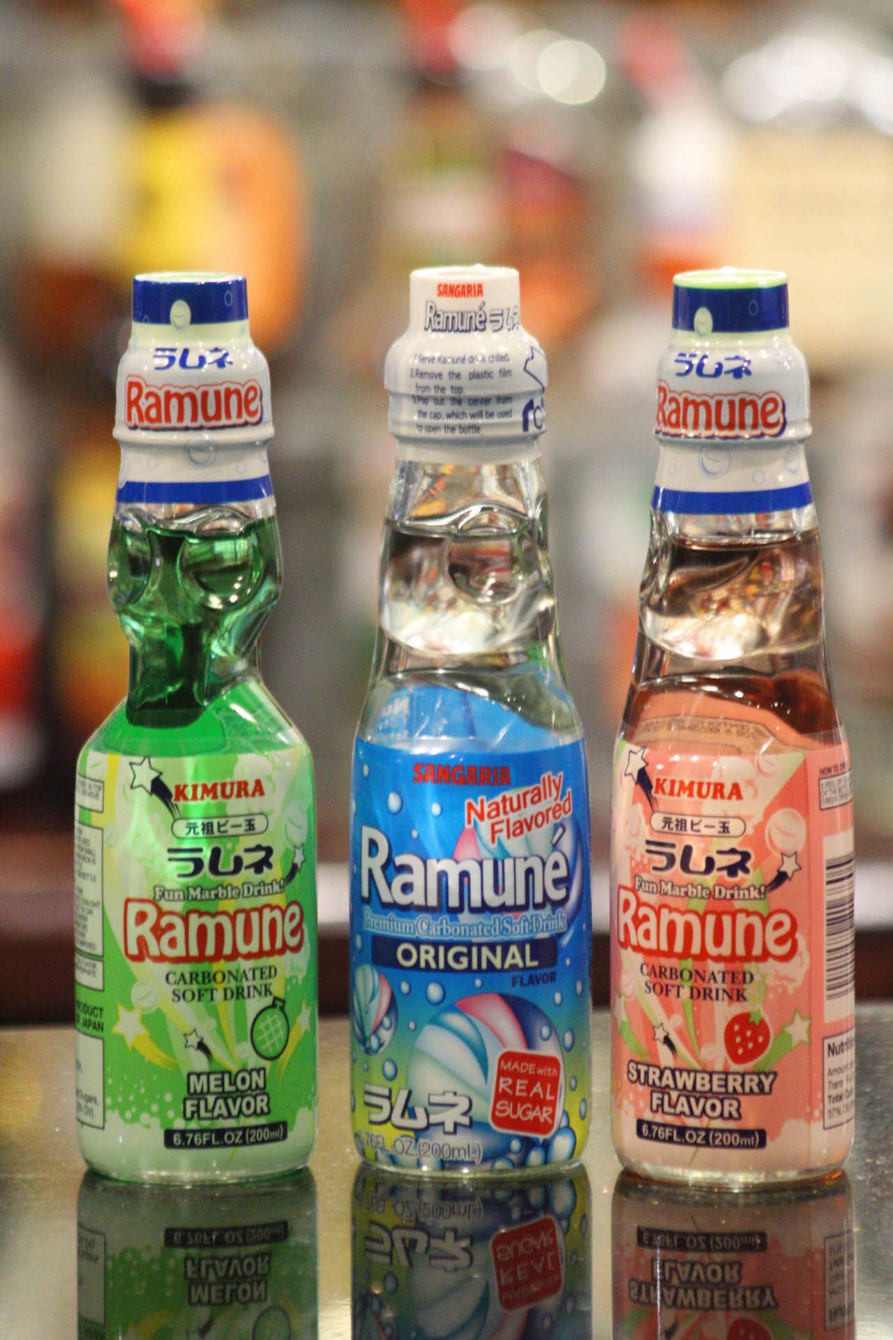 Three bottles of ramune soda are sitting on a table.