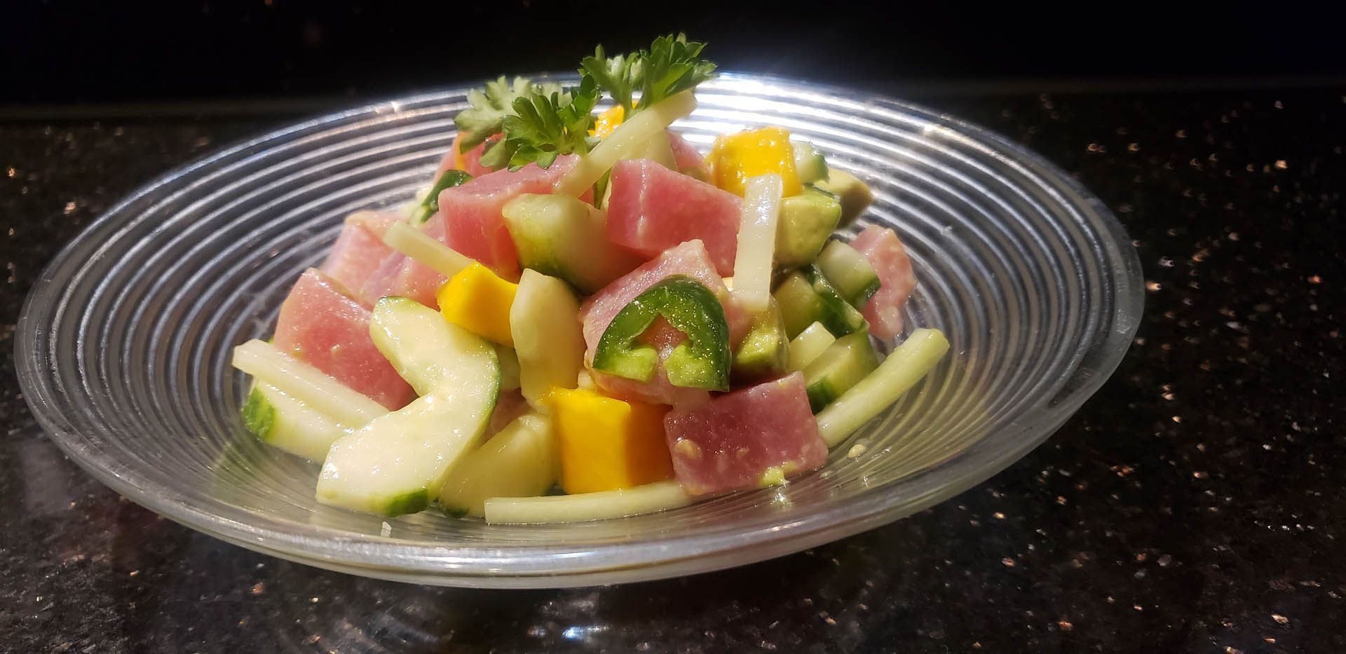 A close up of a salad in a glass bowl on a table.