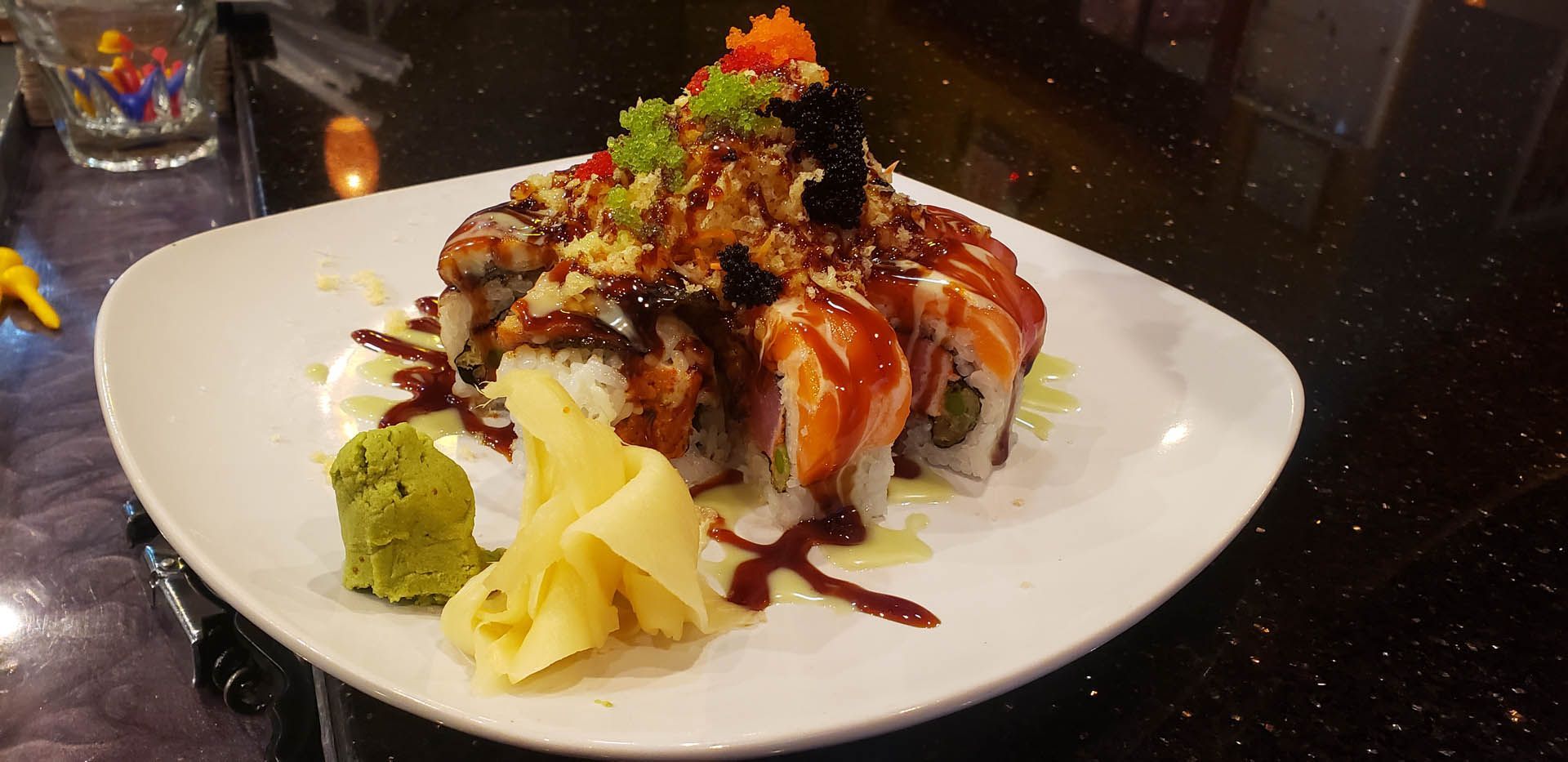 A white plate topped with sushi and wasabi on a table.