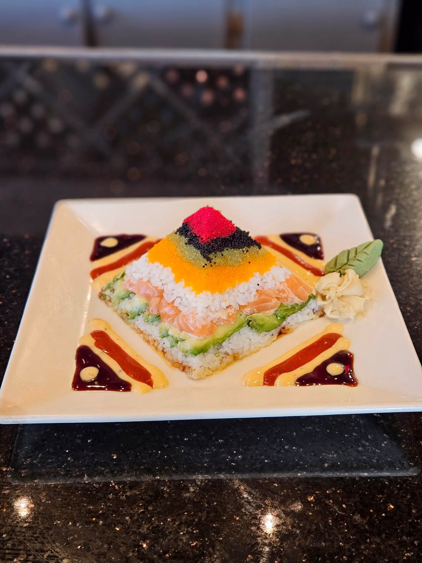 A white plate topped with a sushi pyramid on a counter.