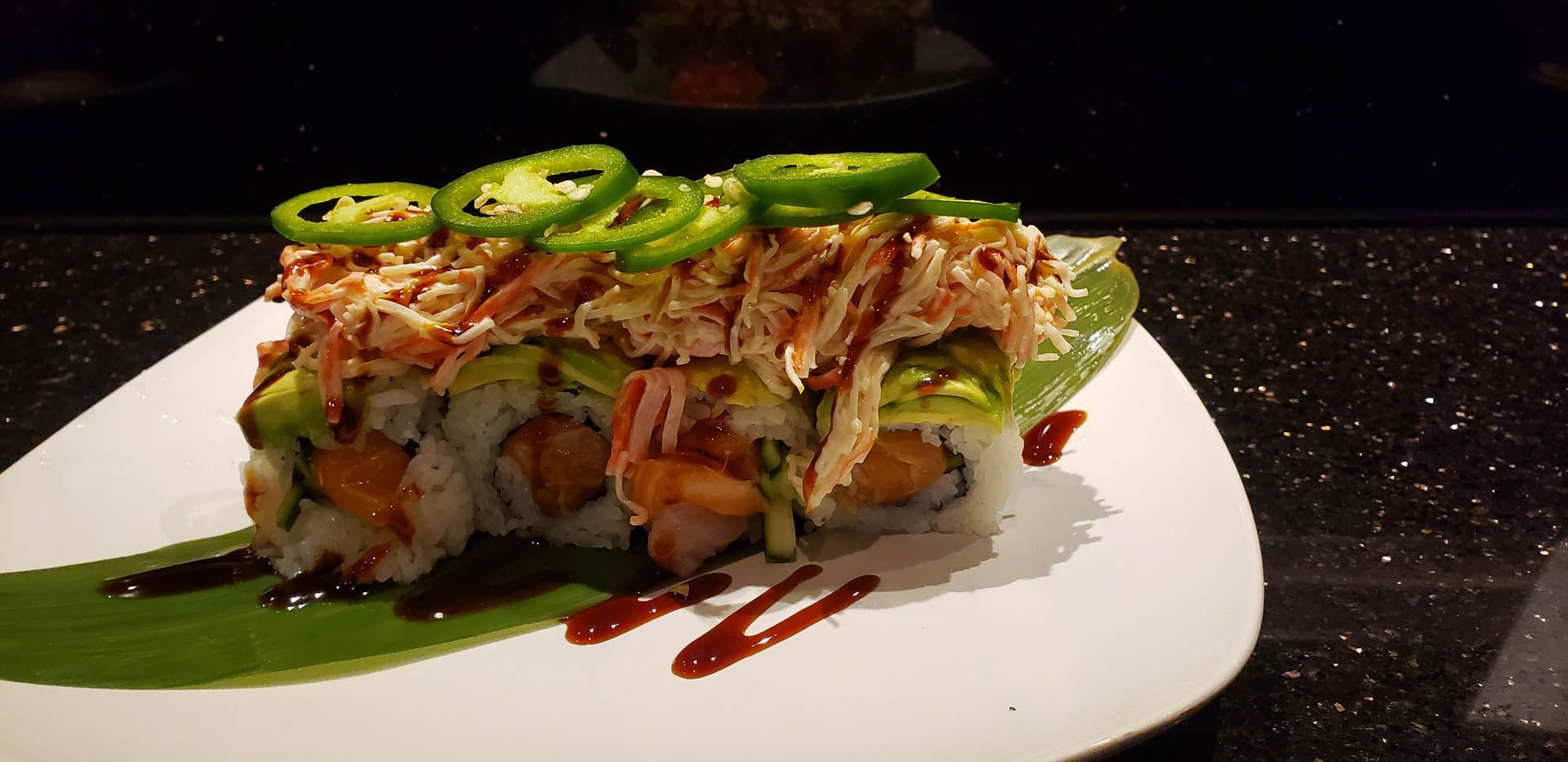 A close up of a sushi roll on a white plate on a table.