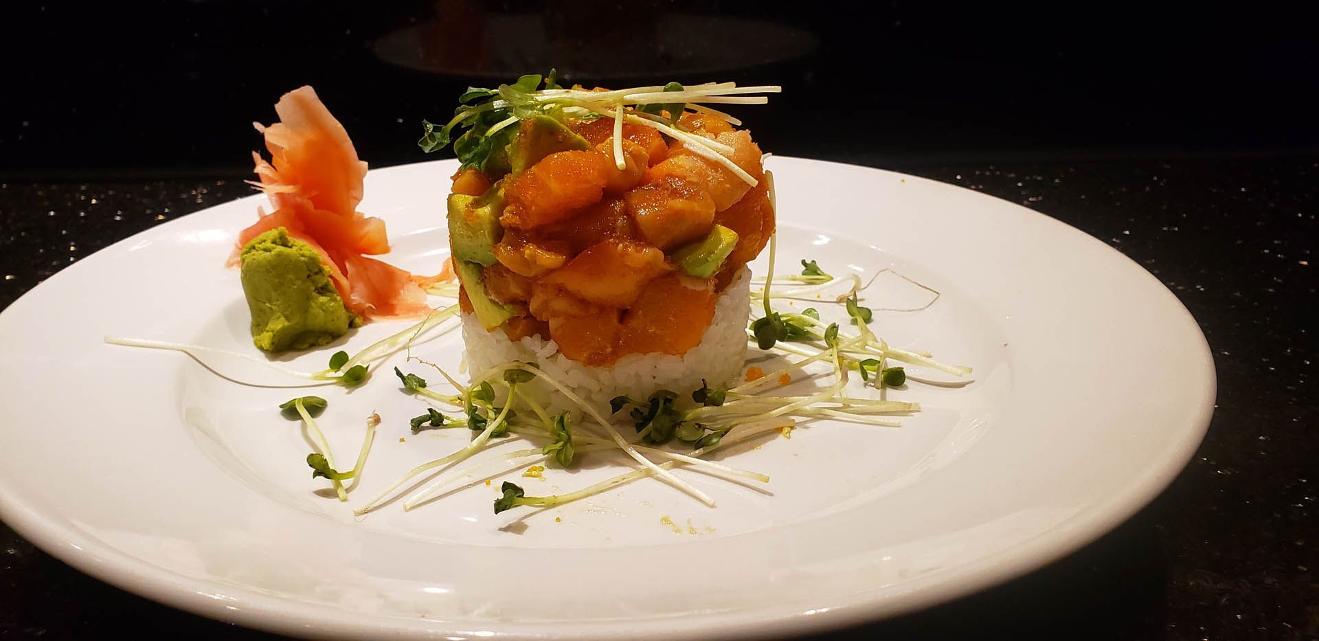 A white plate topped with a stack of food on a table.