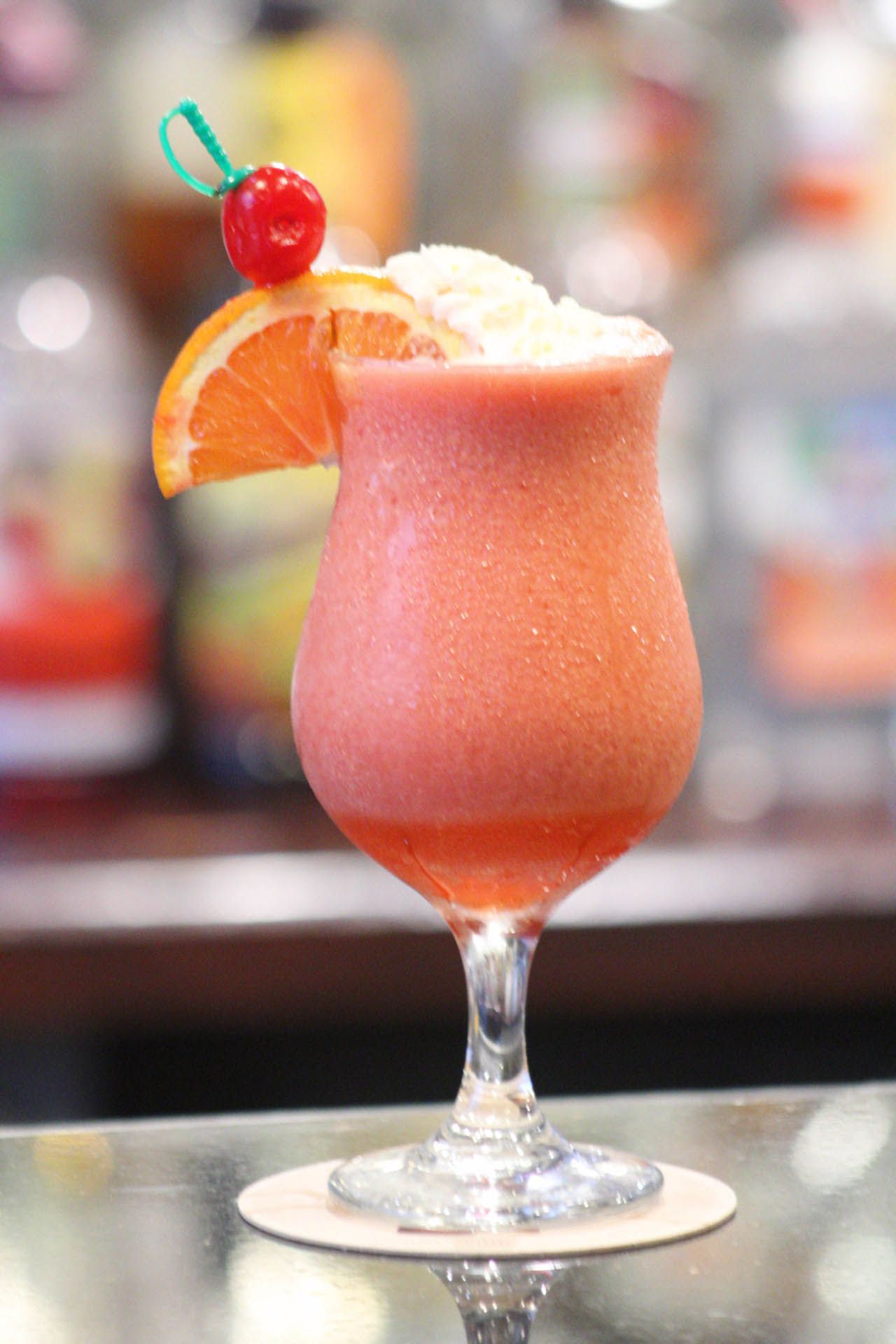 A glass of orange juice with a cherry on top