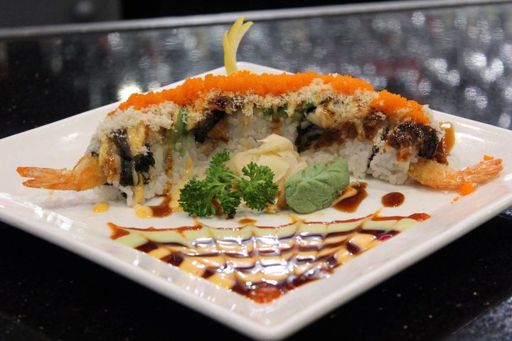 A white plate topped with sushi and sauce on a table.