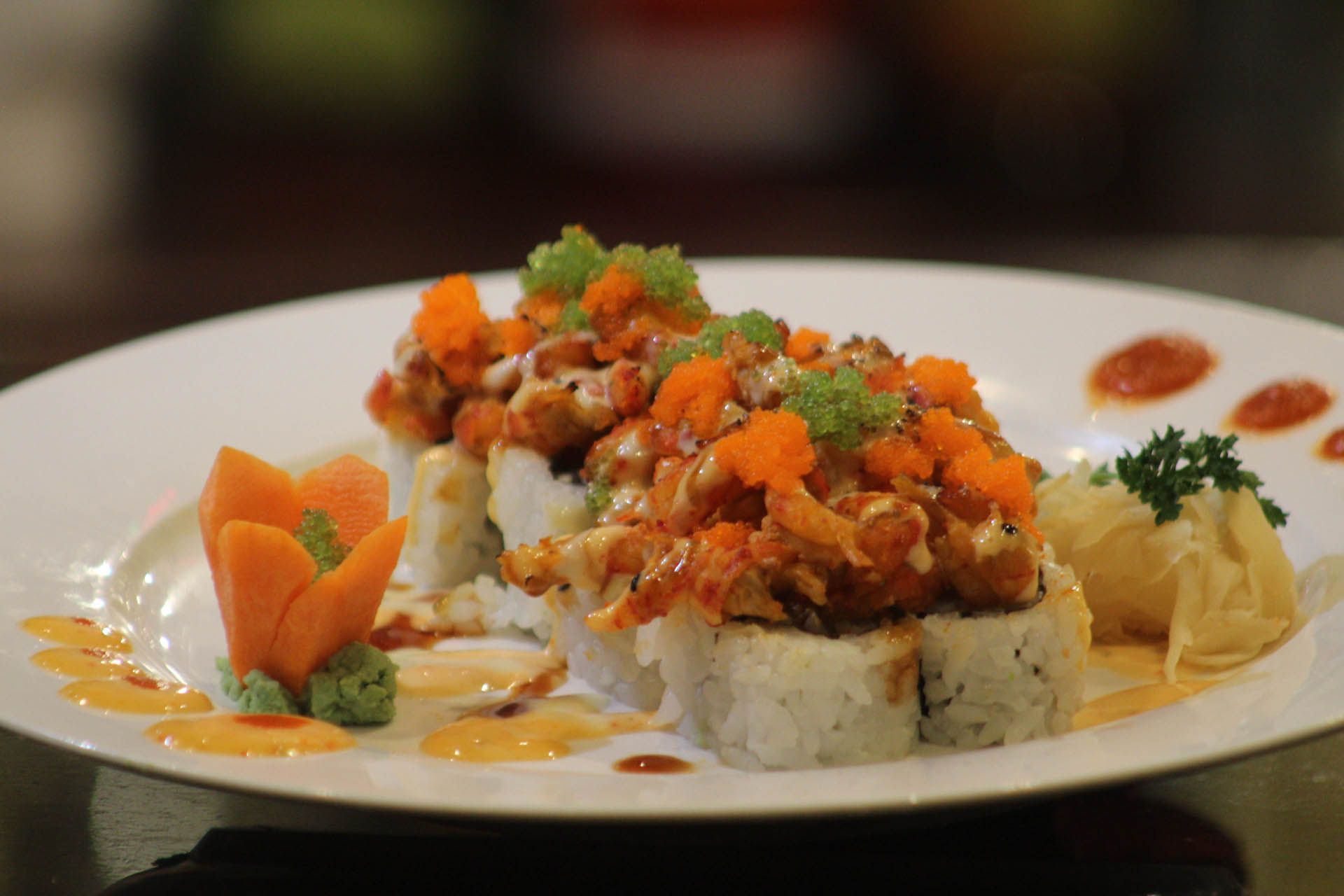 A white plate topped with sushi and vegetables on a table.