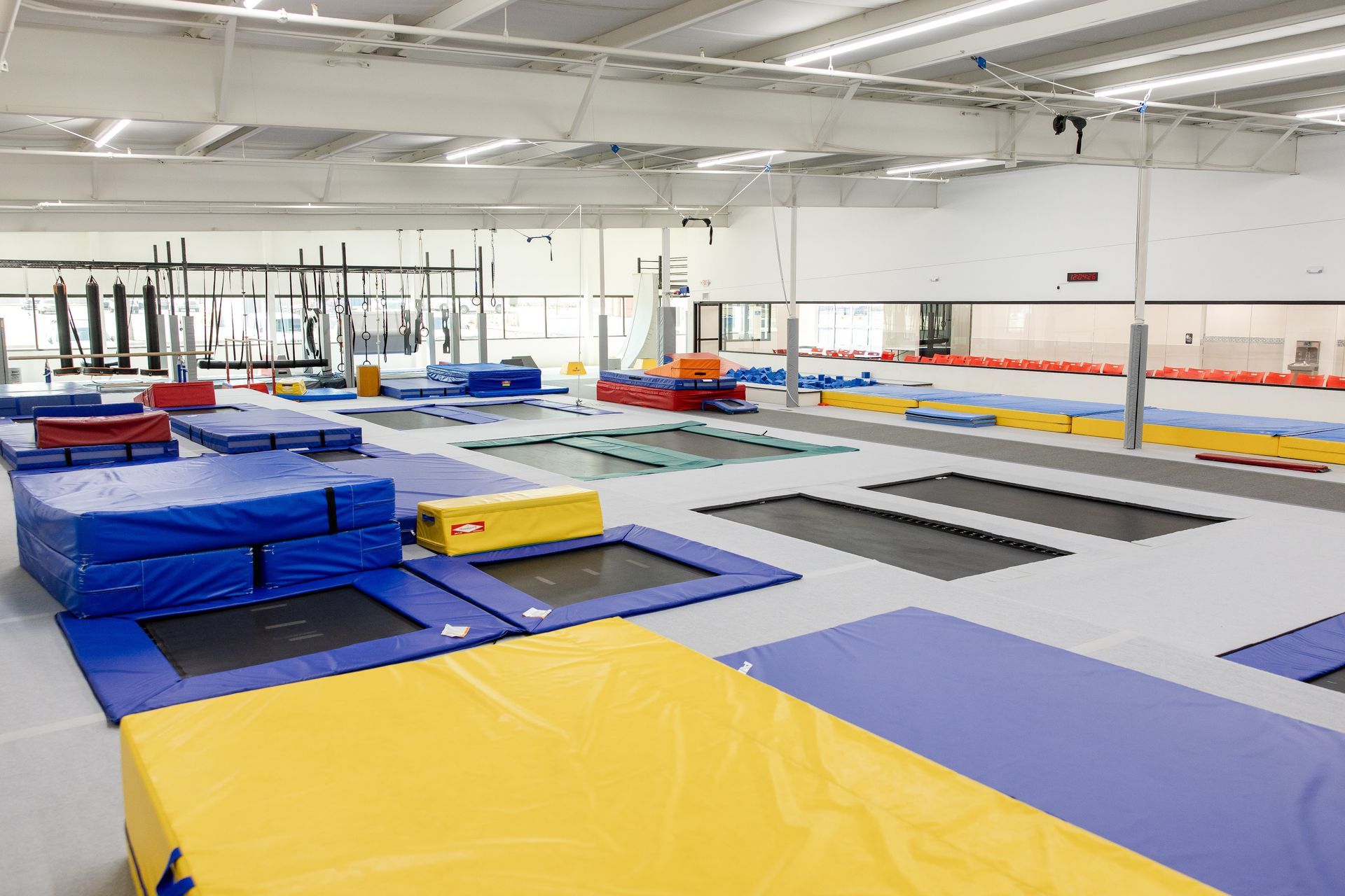 Indoor gymnastics gym with trampolines, padded mats, and foam blocks in blue, yellow, and red.