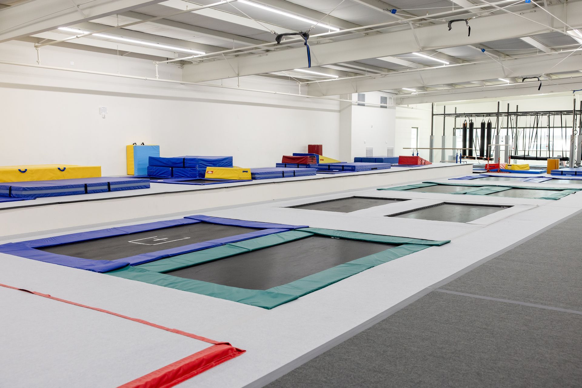 Indoor trampoline park with multiple trampolines and colorful padded seating along the walls