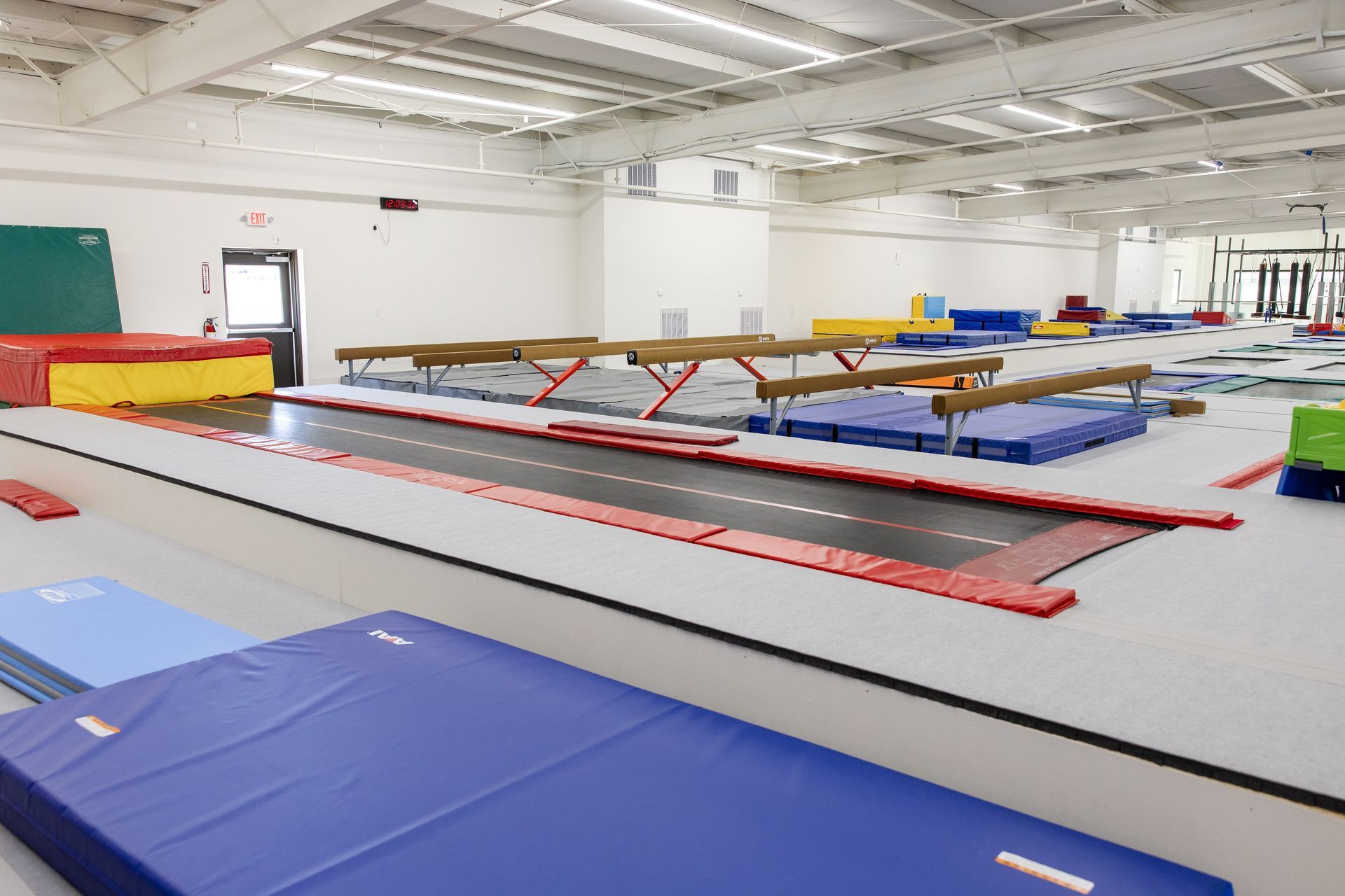 Indoor gymnastics training room with trampolines, mats, and padded equipment