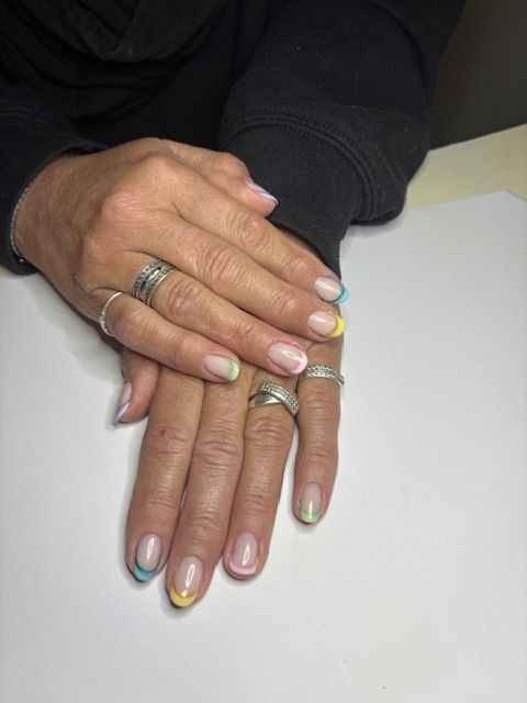 Handen met French manicure nagels, elk gelakt in een andere pastelkleur.