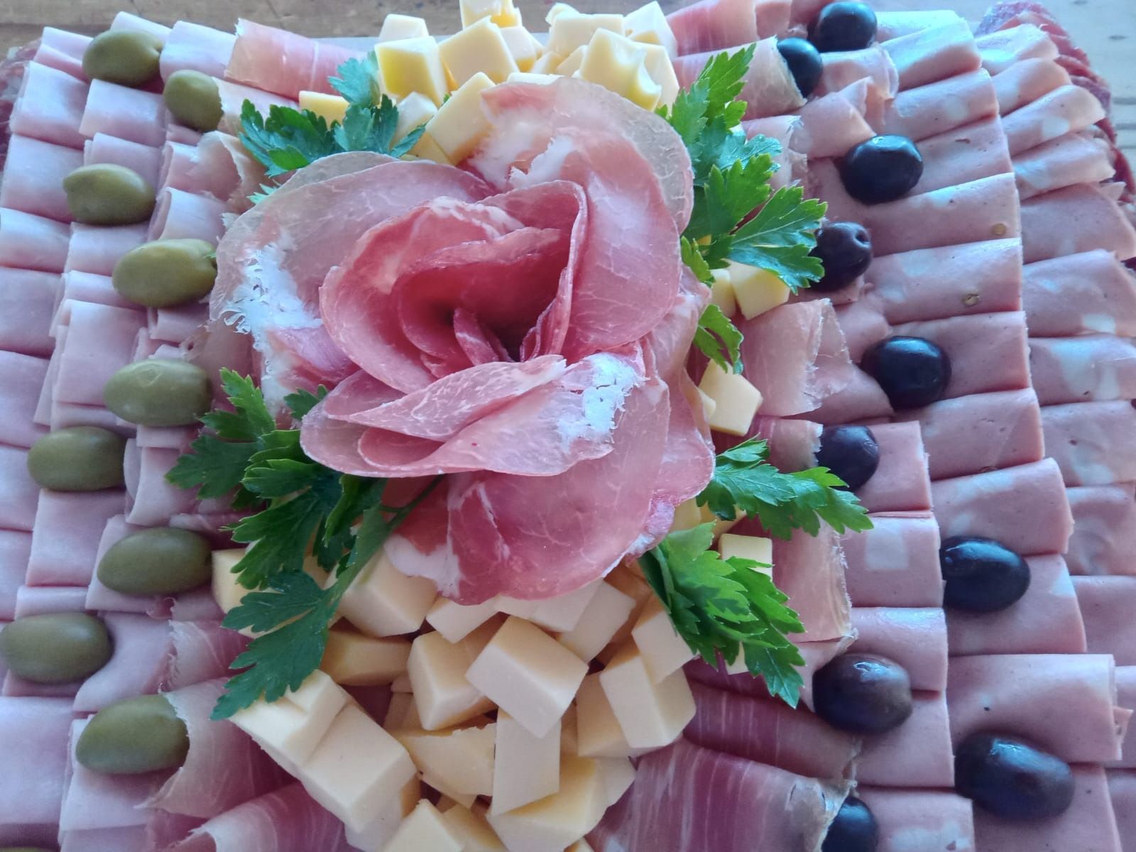 Tabla de embutidos con salami, prosciutto rosa, aceitunas y queso.